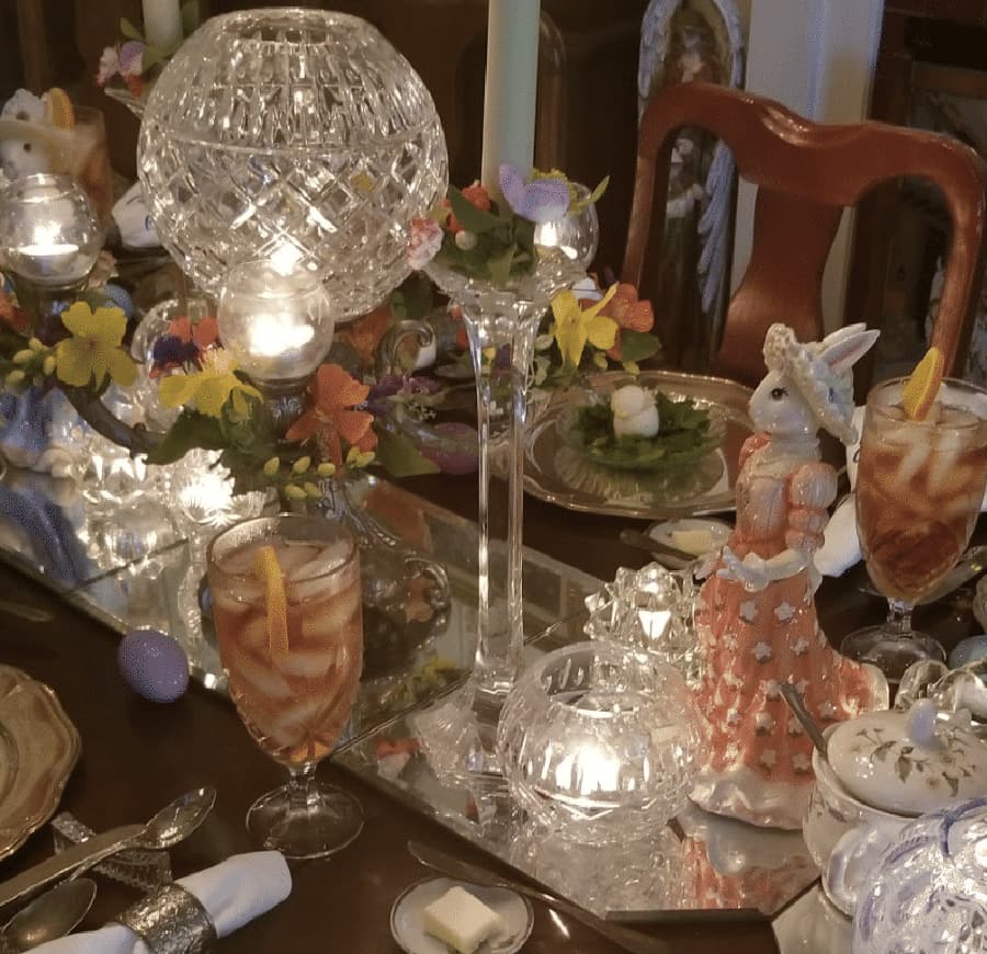 A beautifully arranged dining table featuring crystal decorations, colorful floral accents, and whimsical bunny figurines.