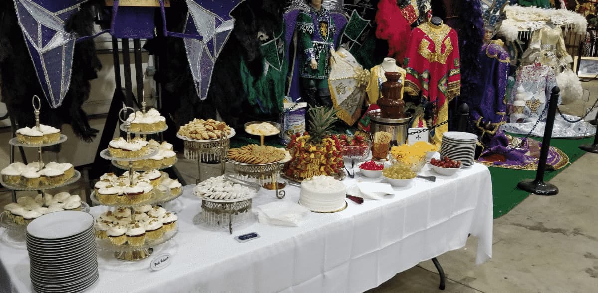 A table filled with a variety of pastries, fruits, and a chocolate fountain, set against a backdrop of colorful costumes.