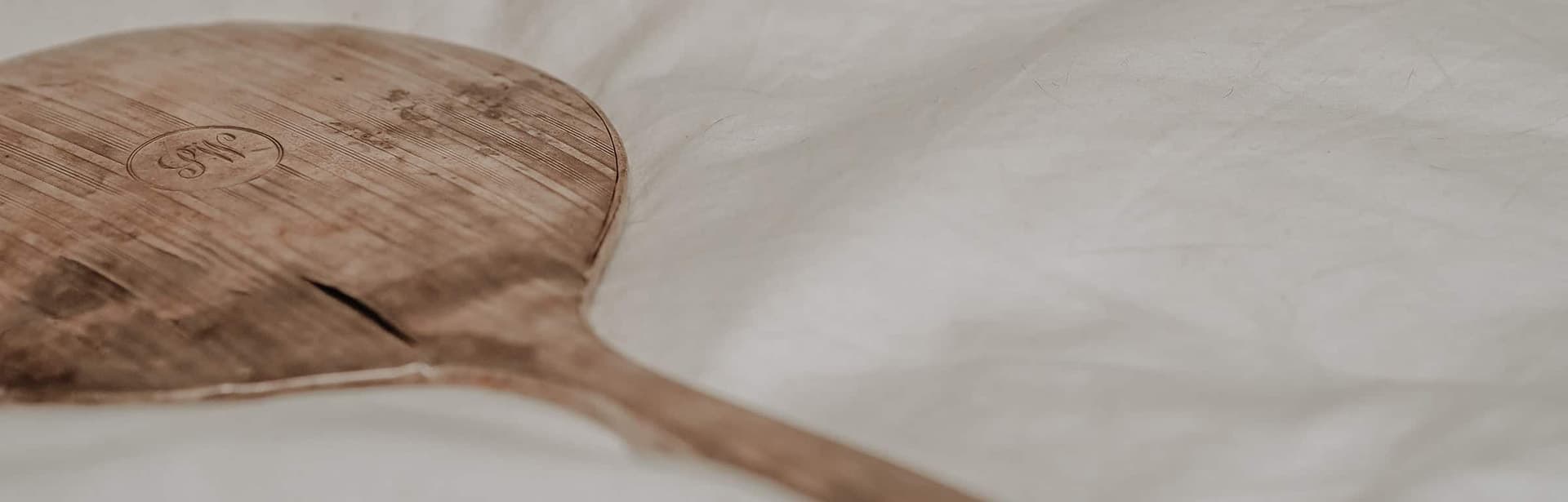 A wooden paddle resting on a soft white surface.