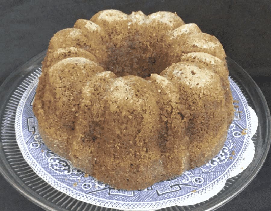 A brown bundt cake on a decorative plate.